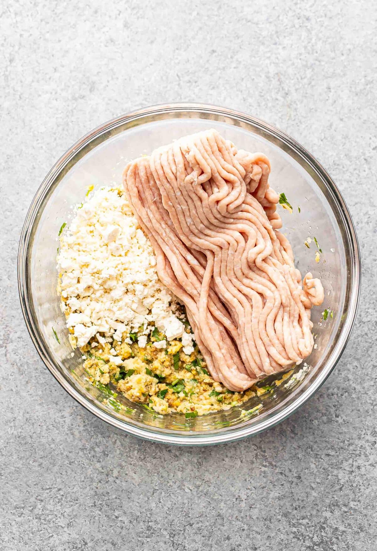 chicken meatball ingredients in glass bowl before being combined together.