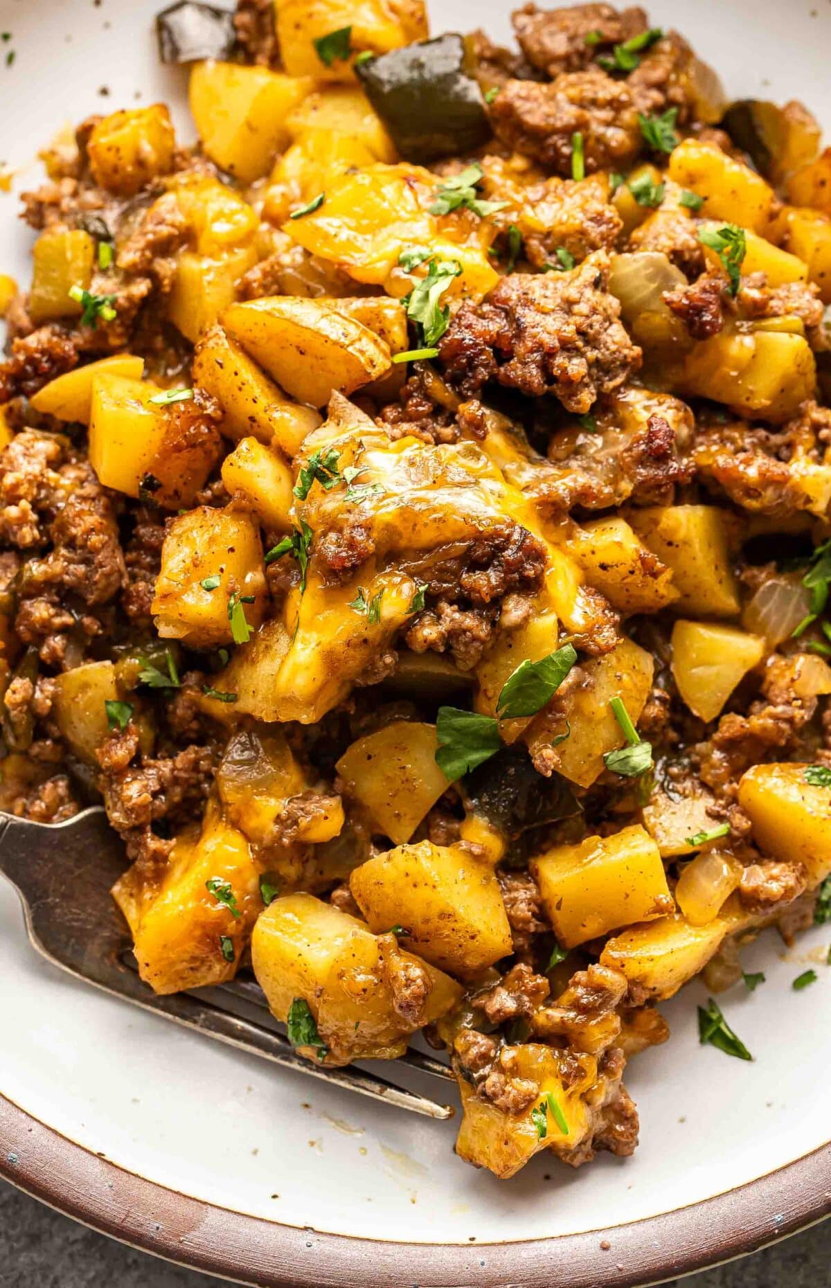 Cheesy ground beef and potato casserole on a white plate.