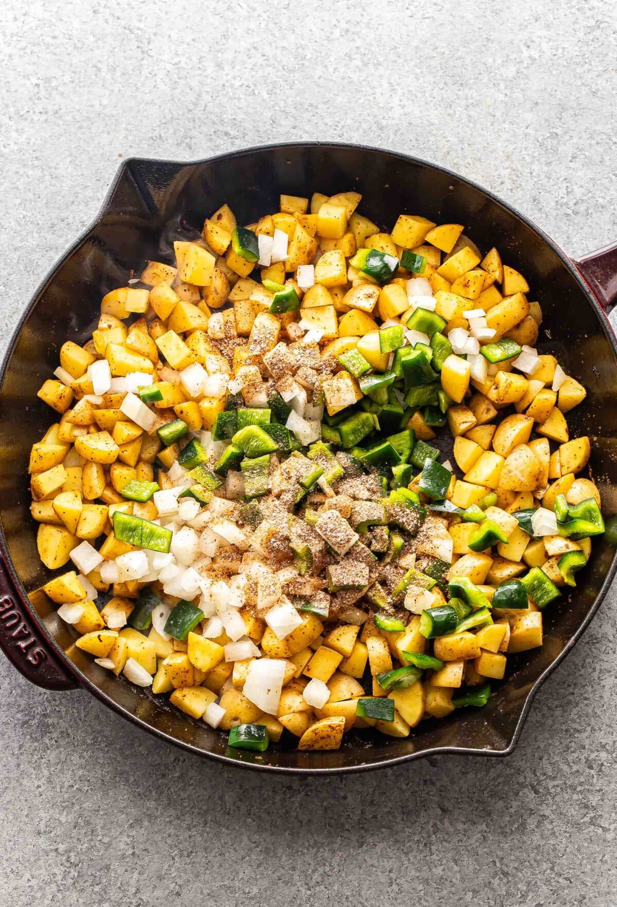 Diced potatoes, onion, pepper, and spices in a skillet.