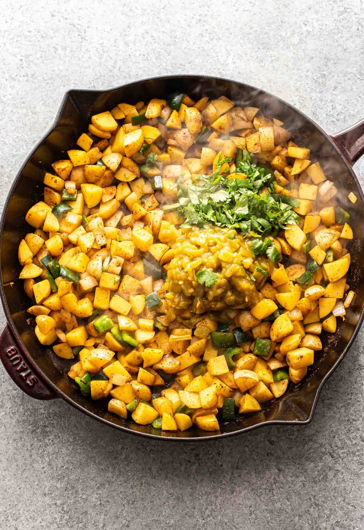 Diced potatoes, green chiles, and cilantro in a skillet.