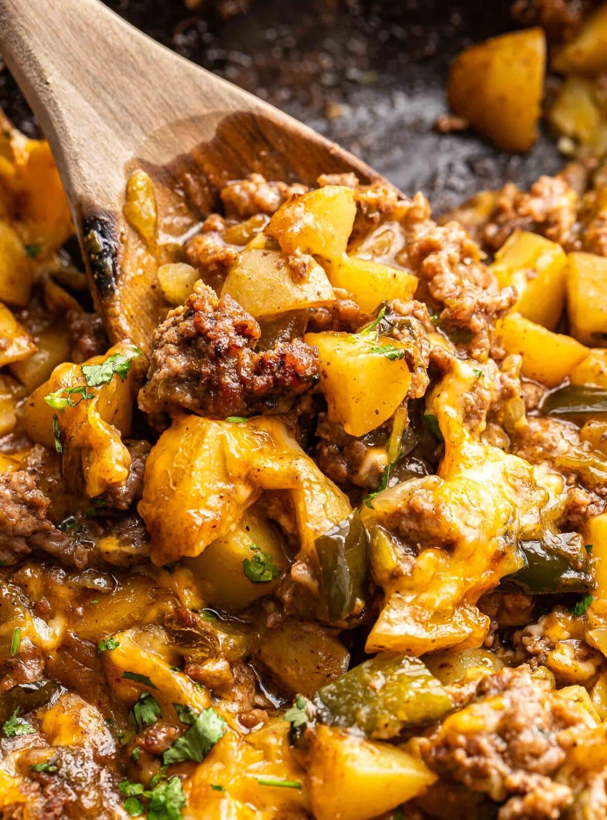 Wooden spoon scooping up southwest ground beef potato casserole.