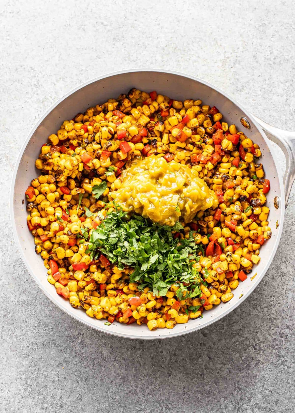 Corn, peppers, green chiles, and cilantro in a skillet.