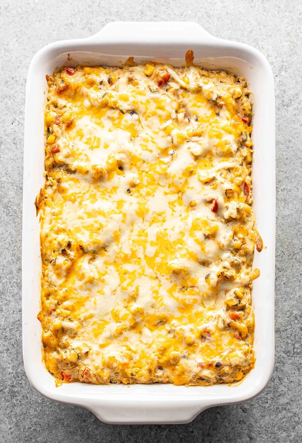 Baked cheesy corn dip in a rectangular white casserole dish.