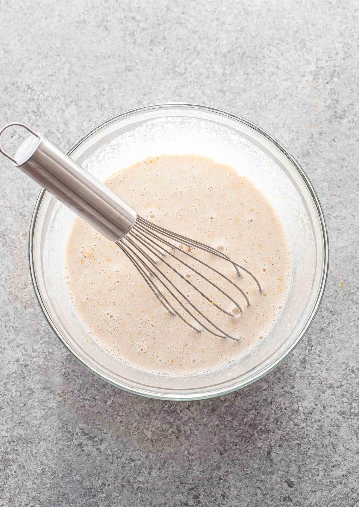 Wet ingredients for peanut butter overnight oats in a mixing bowl with a whisk.
