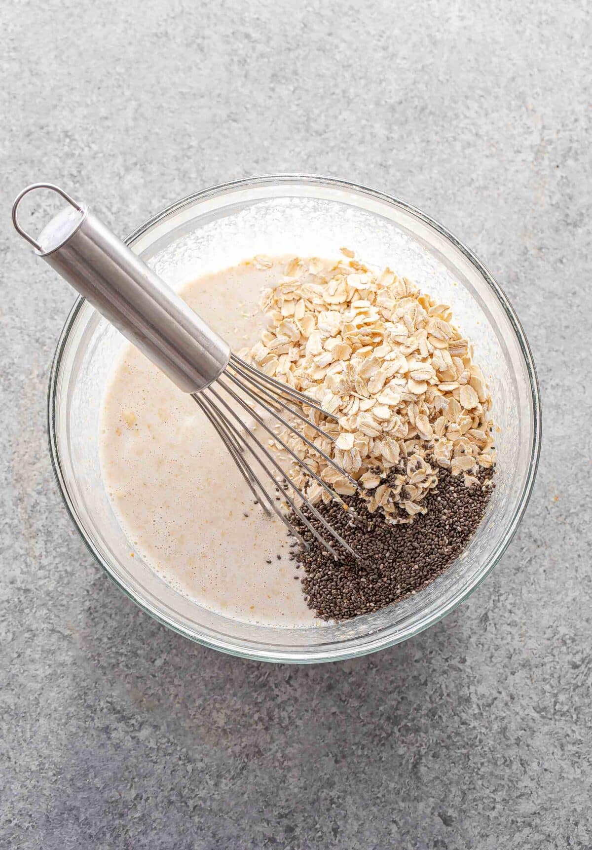 A glass bowl with the overnight oats mixture in it. The oats and chia seeds are on top and haven't been mixed in.