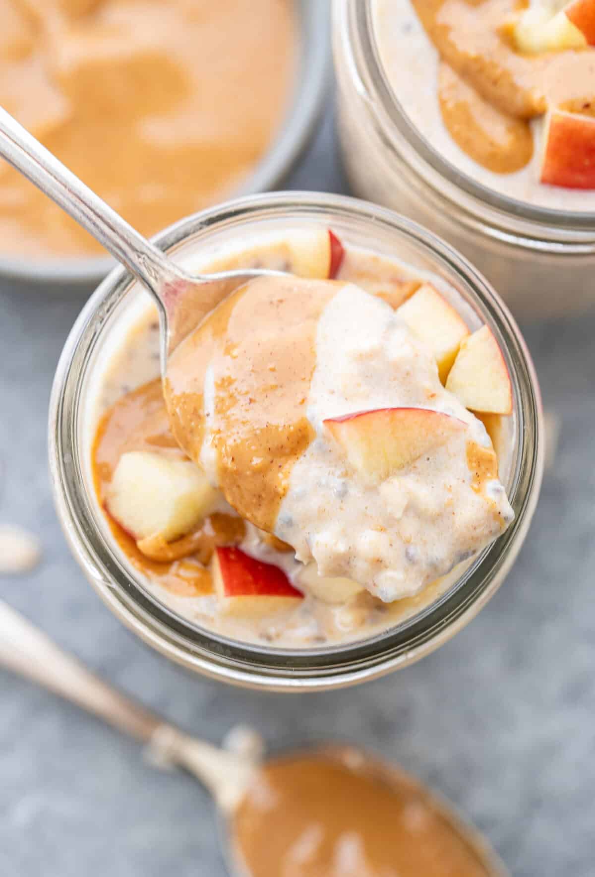 Spoon holding peanut butter overnight oats resting on top of the jar.