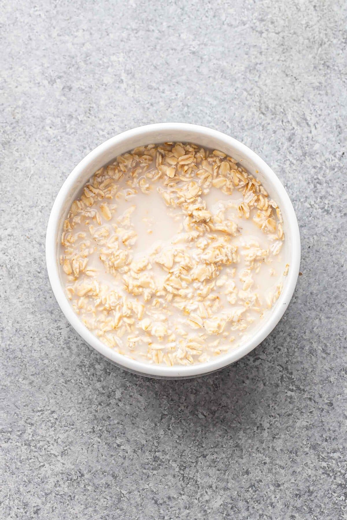 Milk and oats in a white bowl.