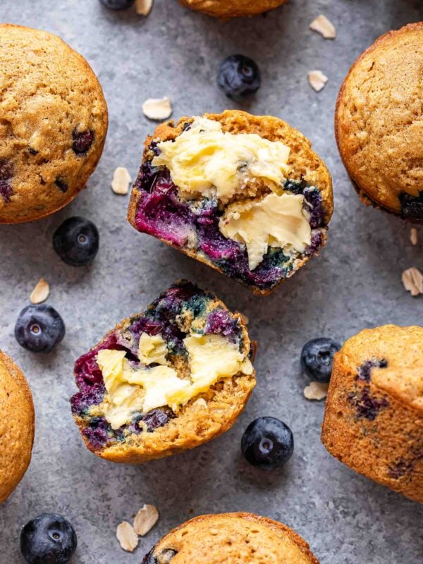 Blueberry oatmeal muffin cut in half with butter on each half.