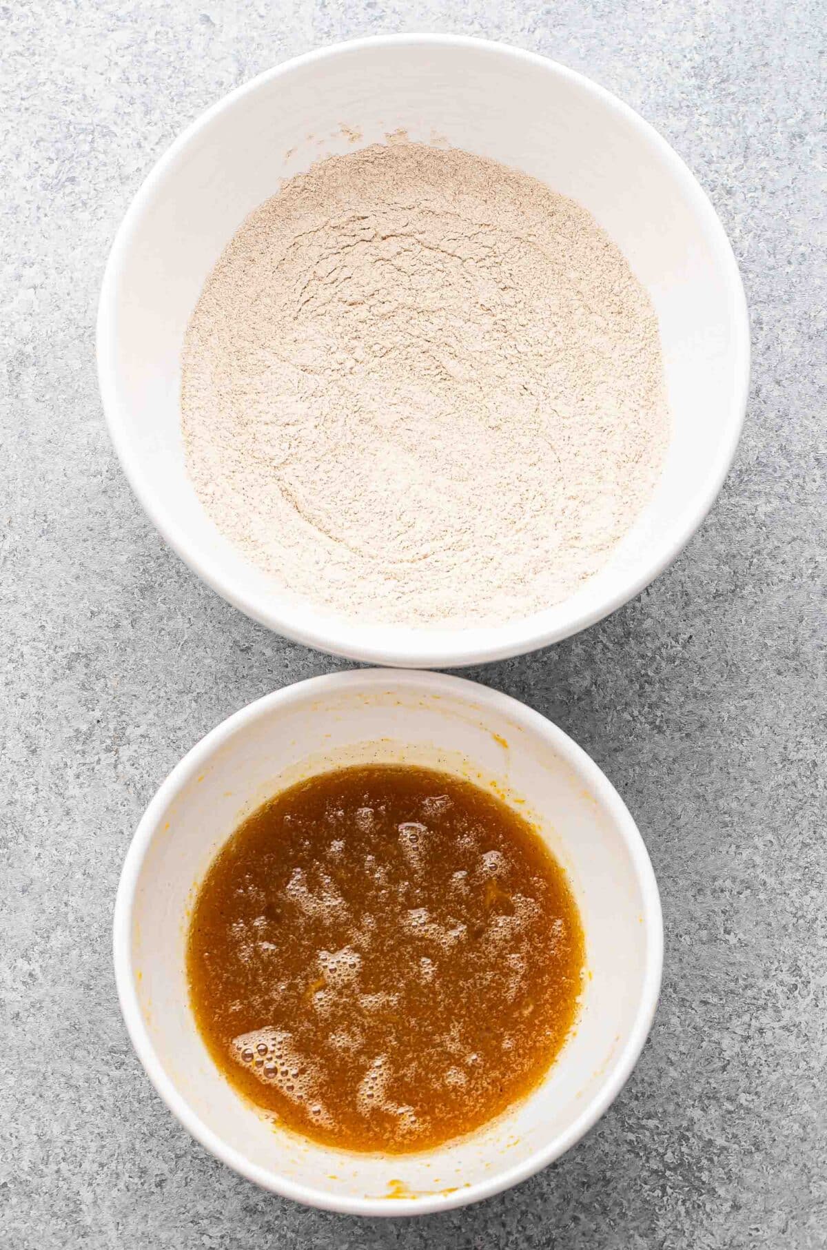 Flour mixture in a white bowl and wet ingredients for blueberry oatmeal muffins in another white bowl.