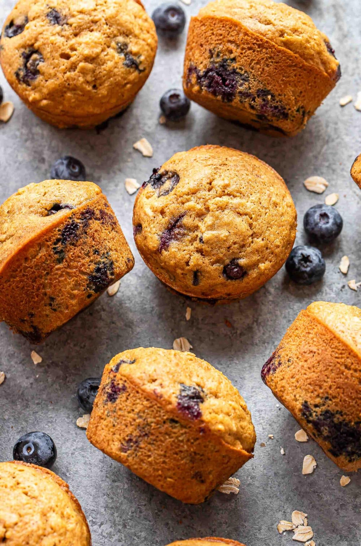 Blueberry oatmeal muffins scattered on a gray surface.