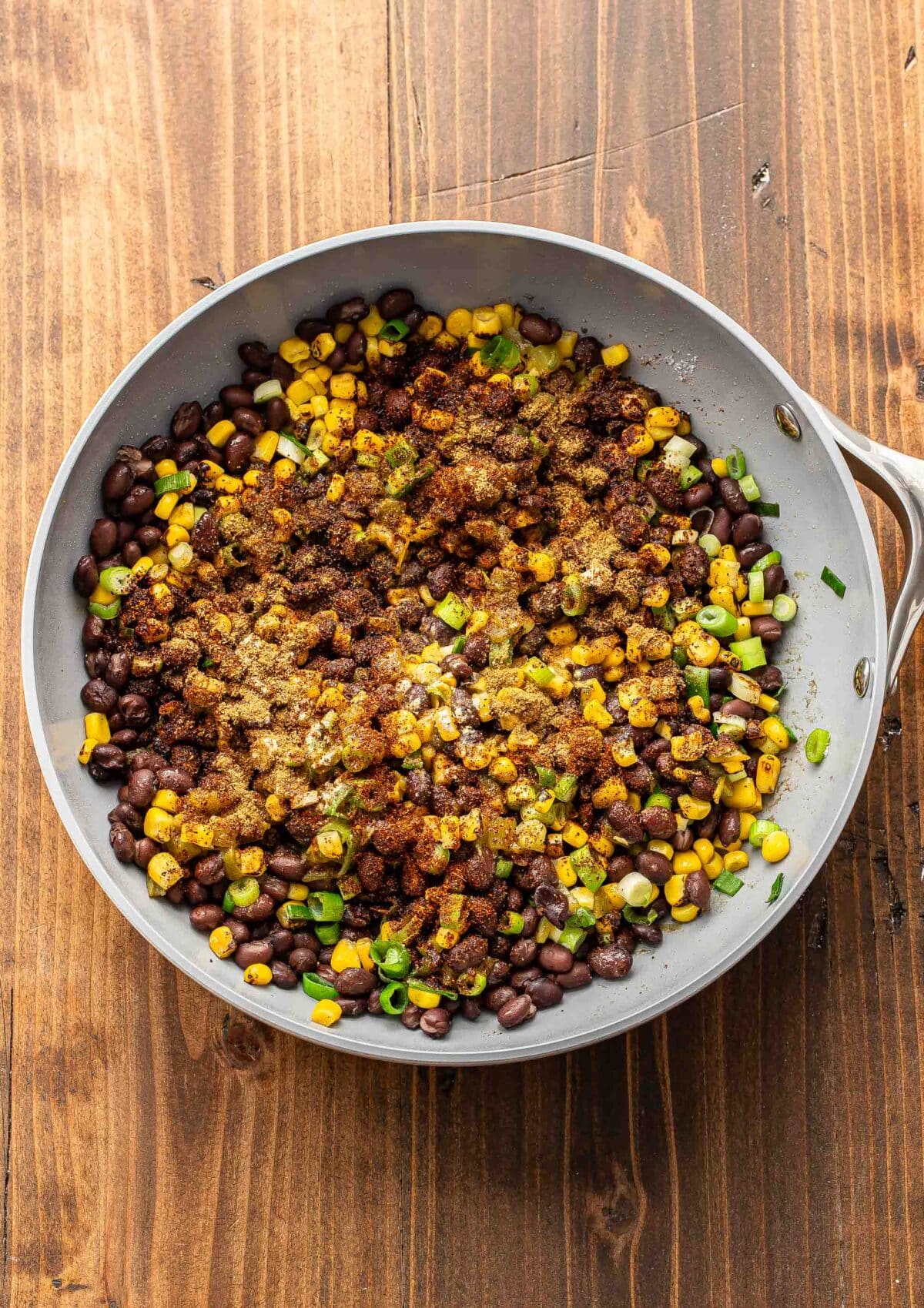 Black beans, corn, green onions, and spices in a skillet.