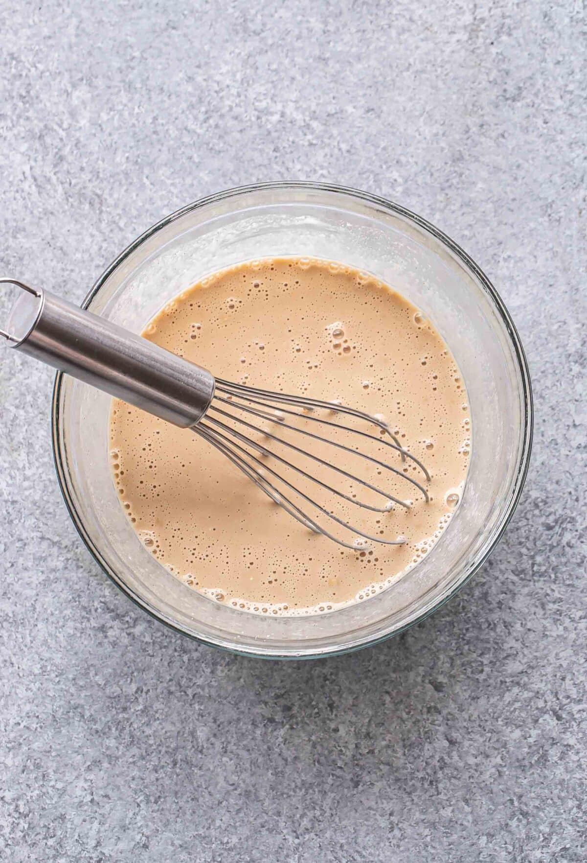 Wet ingredients for coffee overnight oats in a glass mixing bowl with a whisk.