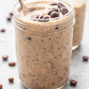 Coffee overnight oats in a glass jar with chocolate chips on top.