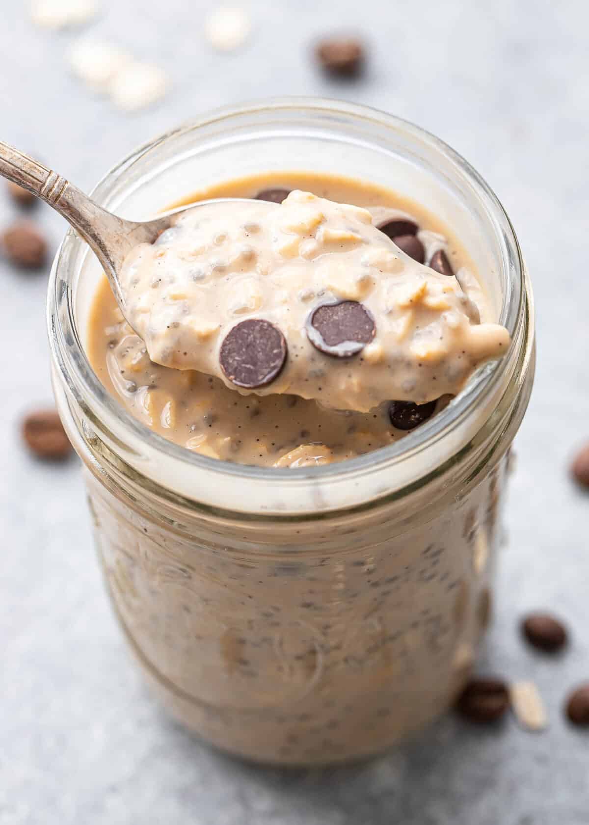 Spoon scooping up coffee overnight oats with chocolate chips on top.