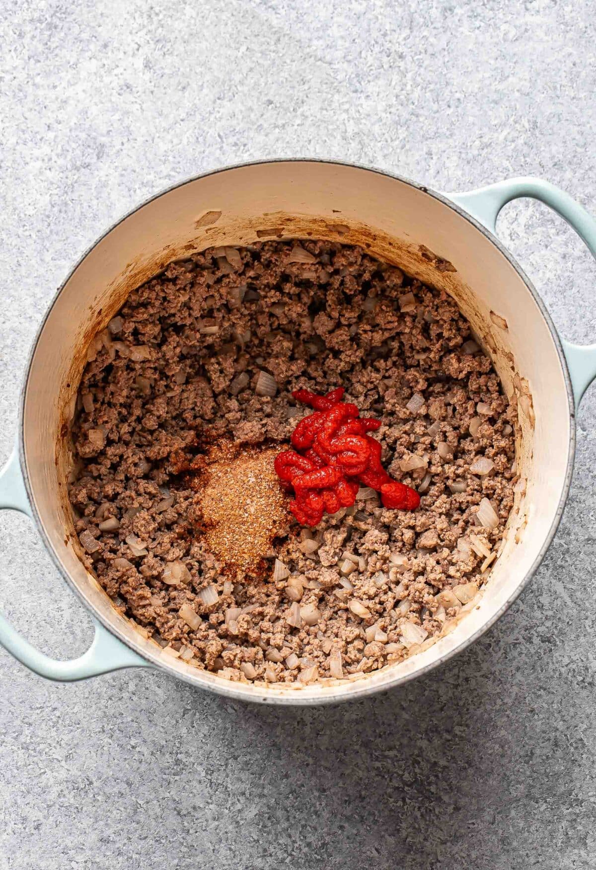 Ground beef, tomato paste, and spices in a pot.