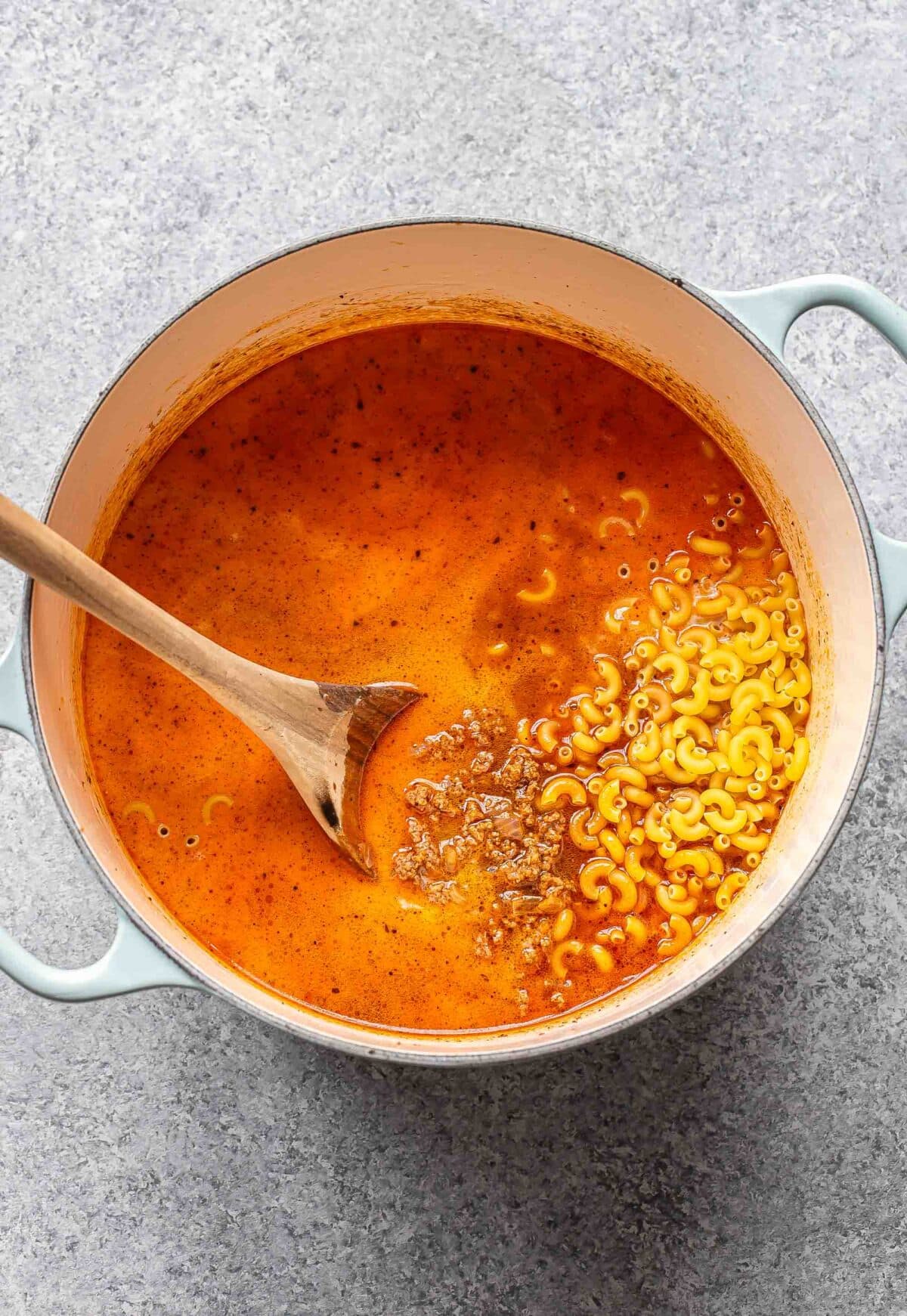 Ground beef, pasta, broth, and milk in a pot.
