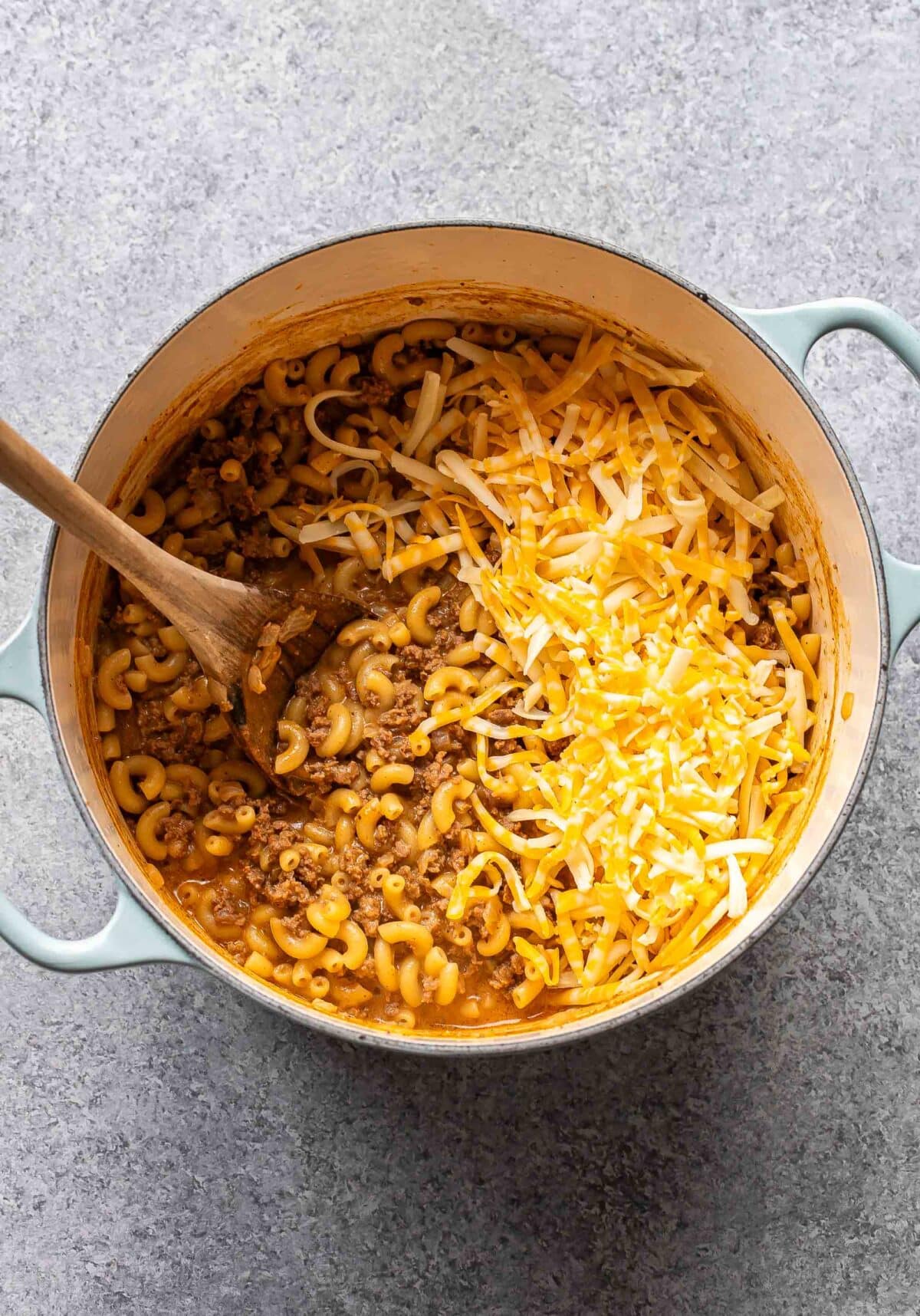 Hamburger helper in a pot with shredded cheese on top.