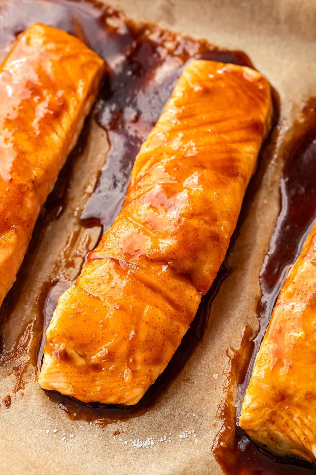 Maple glazed baked salmon fillets on a parchment paper lined sheet pan.