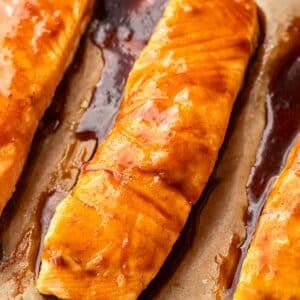 Maple glazed baked salmon fillets on a parchment paper lined sheet pan.
