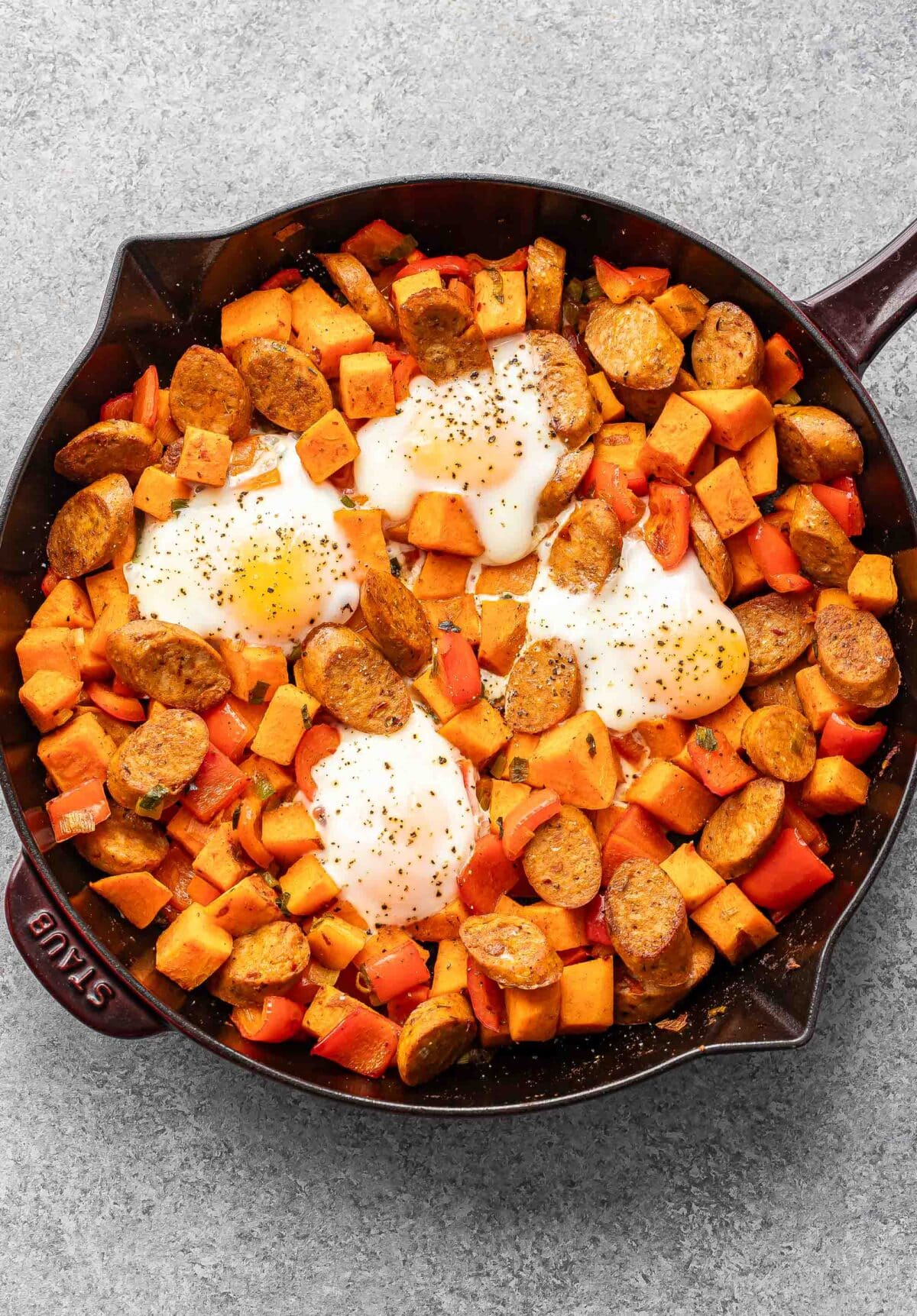 Sweet potato hash in a skillet with 4 baked eggs on top.