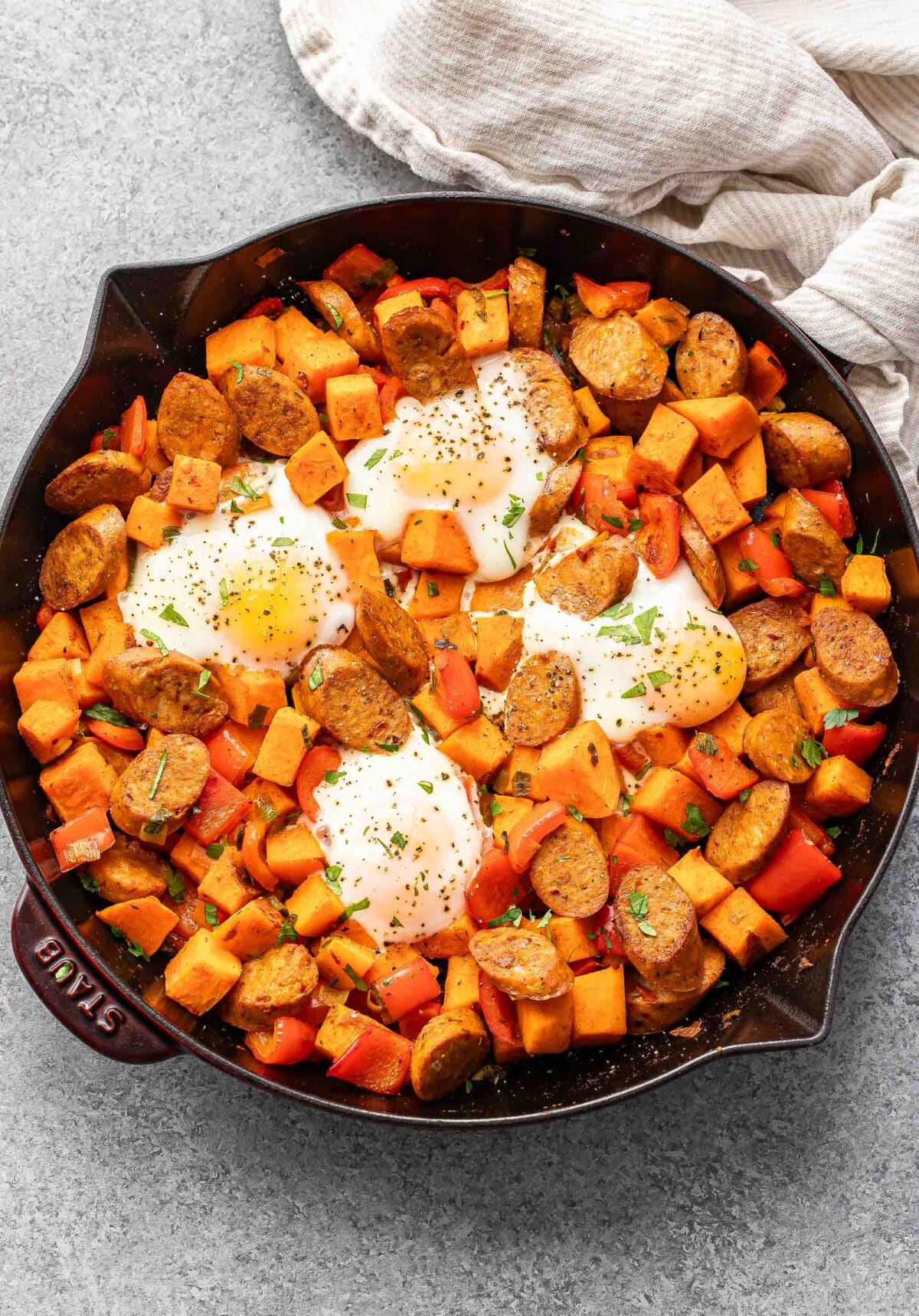 Sweet potato hash in a skillet with 4 baked eggs on top.