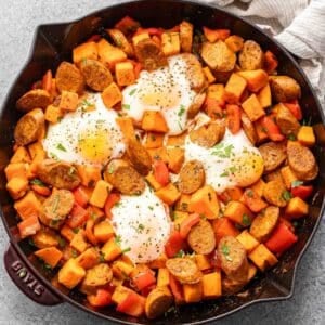 Sweet potato hash in a skillet with 4 baked eggs on top.