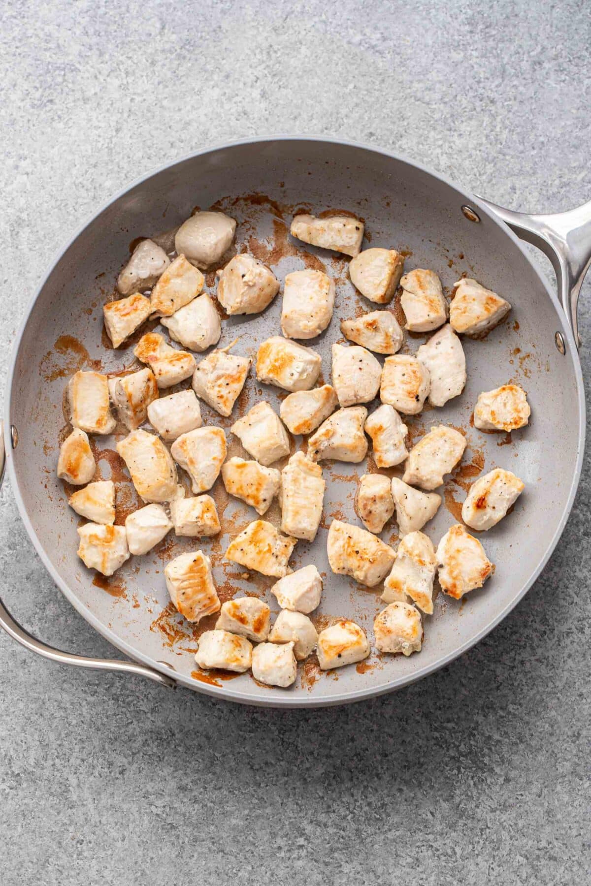 Cooked pieces of chicken in a skillet.