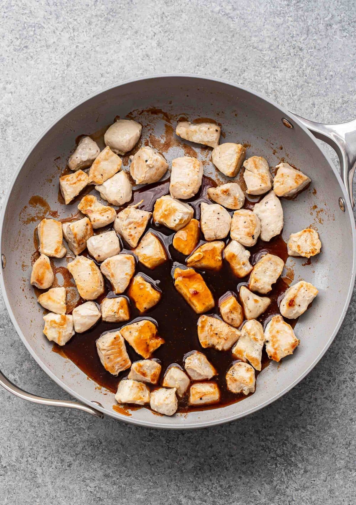 Cooked chicken and teriyaki sauce in a skillet.