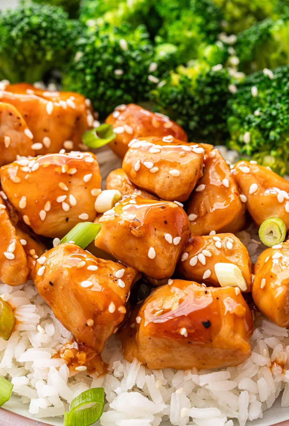 Teriyaki chicken on top of rice with sesame seeds and green onions.