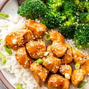 Teriyaki chicken on top of rice with steamed broccoli on the side.
