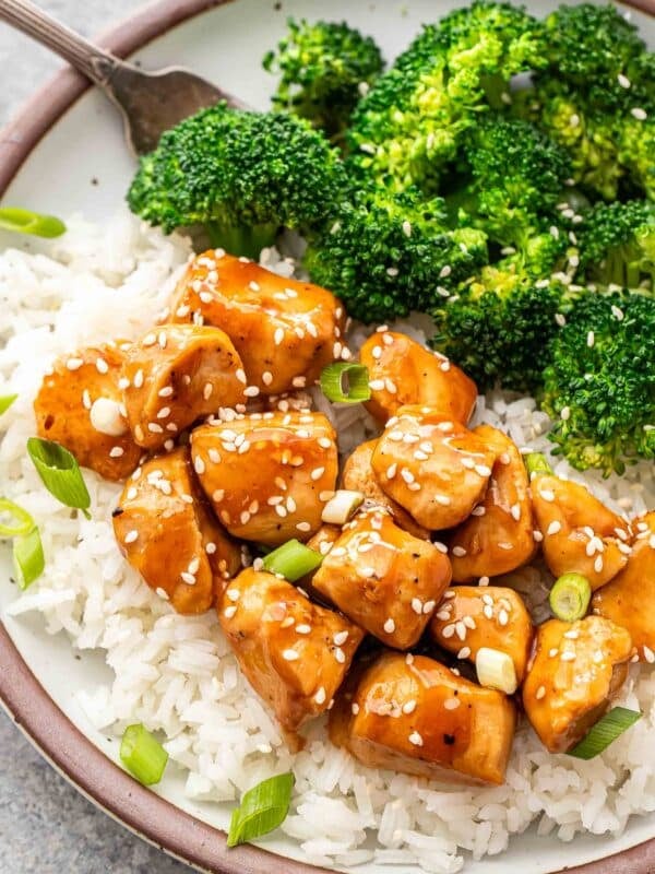 Teriyaki chicken on top of rice with steamed broccoli on the side.