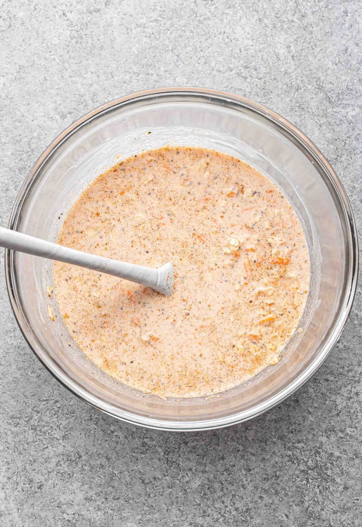 Carrot cake overnight oats mixture in a glass bowl before being refrigerated.