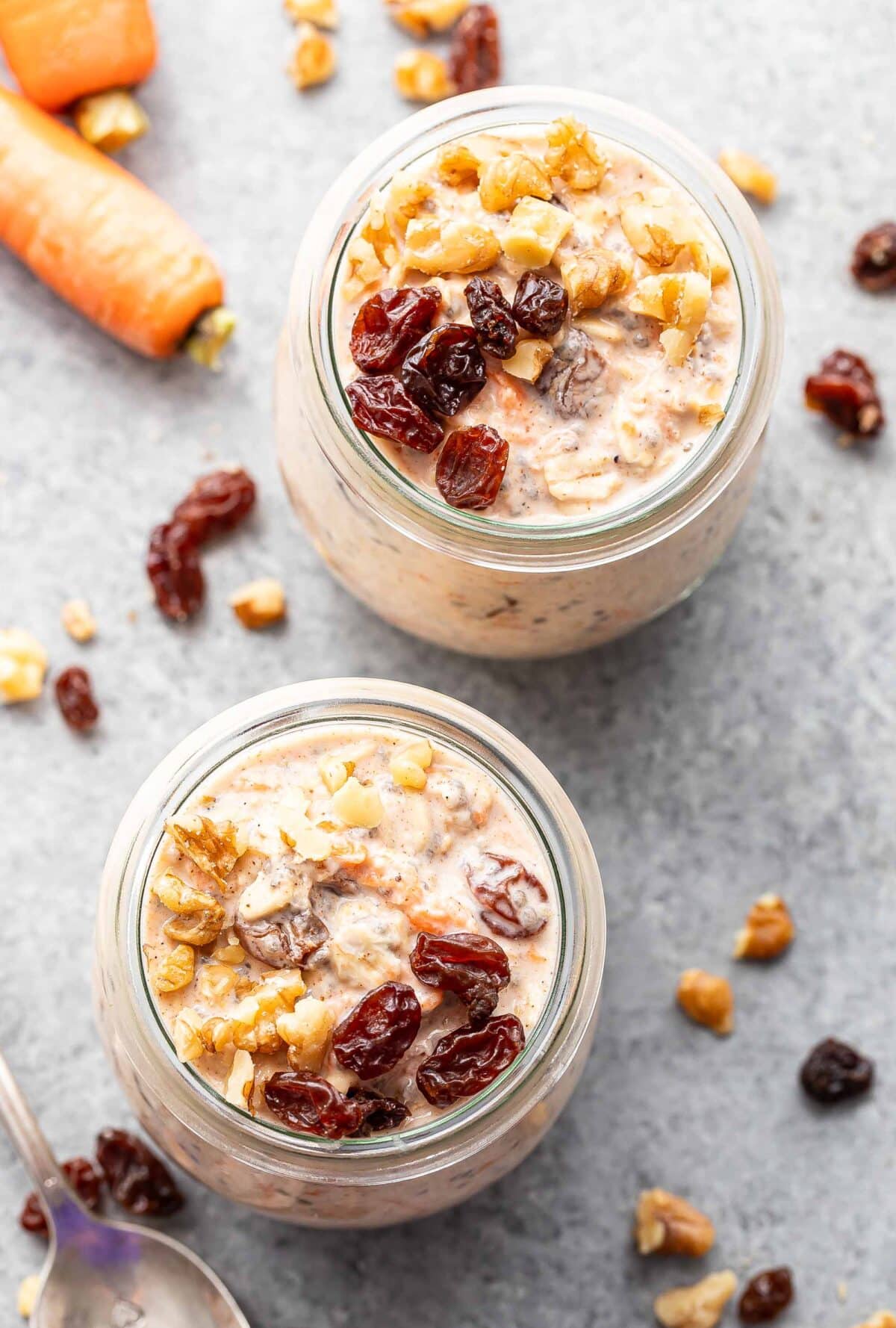 Two jars of carrot cake overnight oats topped with raisins and walnuts.