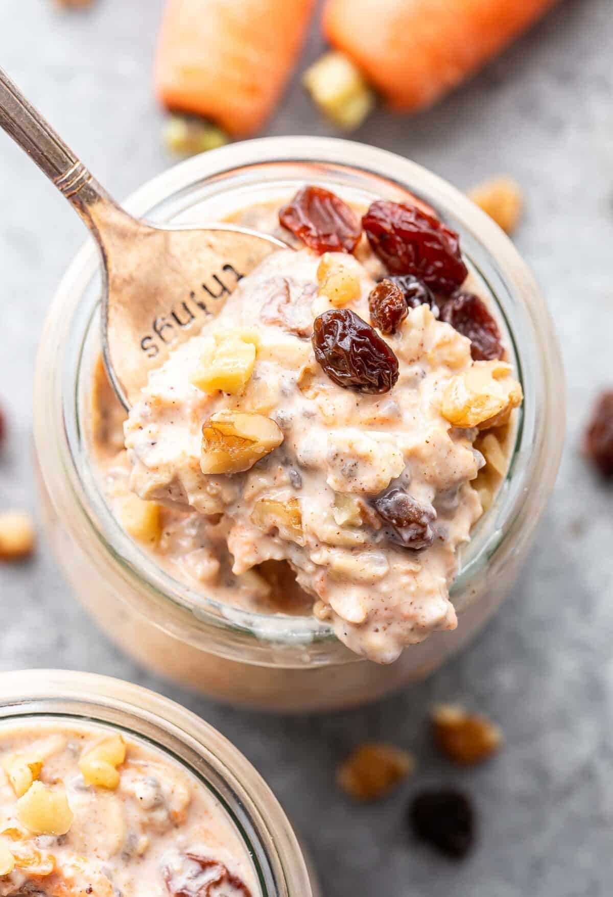 A jar of carrot cake overnight oats with a spoon scooping out some of them.