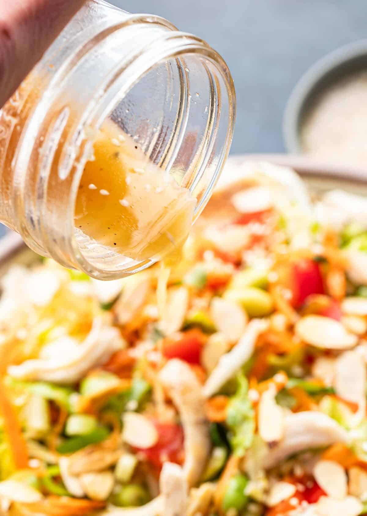 Sesame vinaigrette being poured onto the Chinese chicken salad.