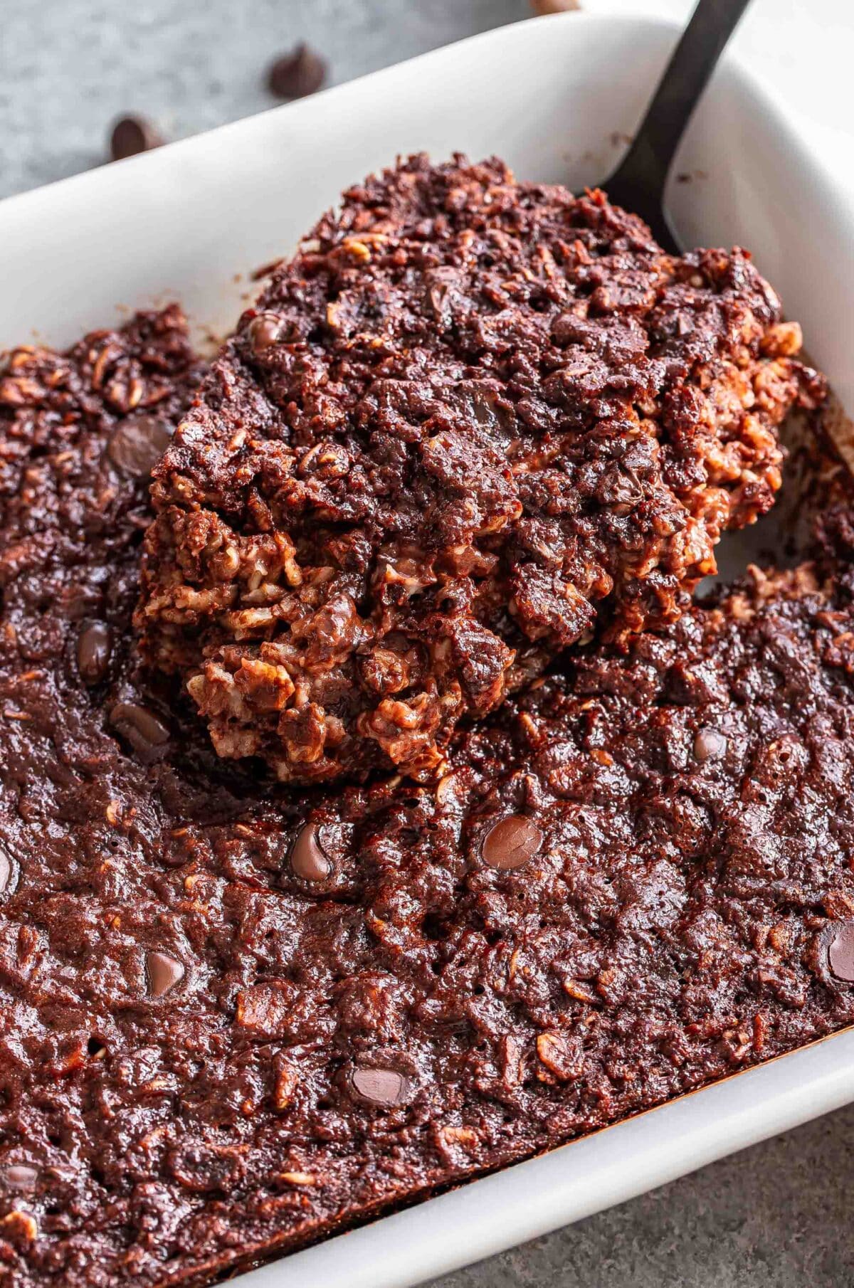 A piece of chocolate baked oatmeal being scooped out of the baking dish.