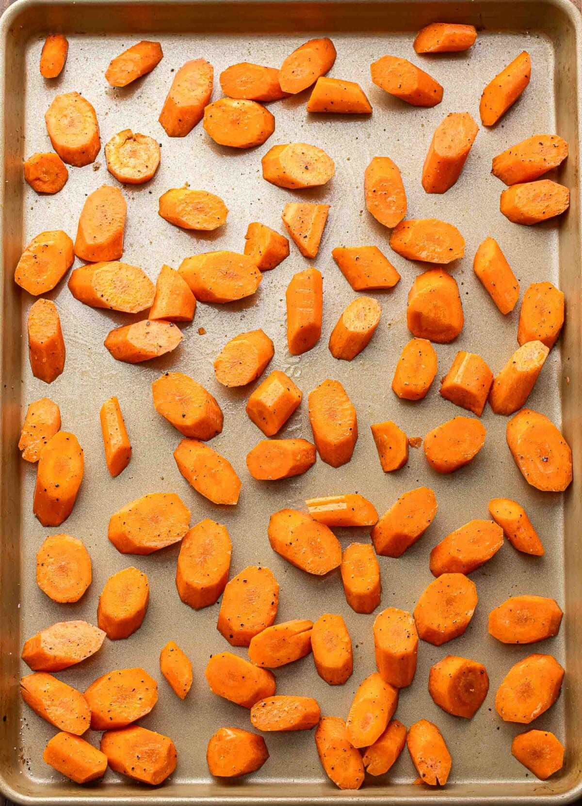 Chunks of carrots on a baking sheet before they've been roasted.