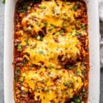 Baked salsa chicken topped with melted cheese, green onions, and cilantro in a white casserole dish.