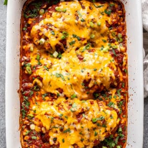 Baked salsa chicken topped with melted cheese, green onions, and cilantro in a white casserole dish.