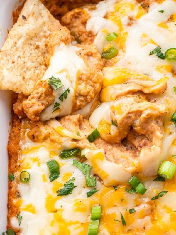 Tortilla chip scooping up cheesy bean dip.