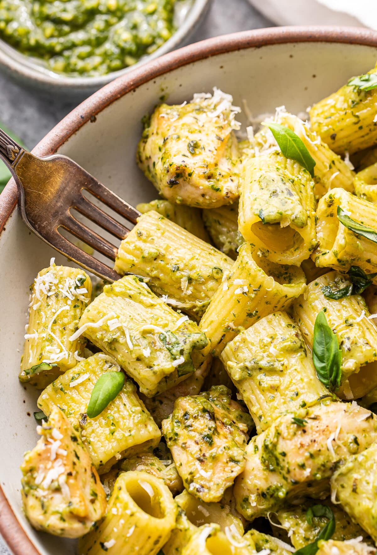 Chicken pesto pasta in a white bowl with a fork.