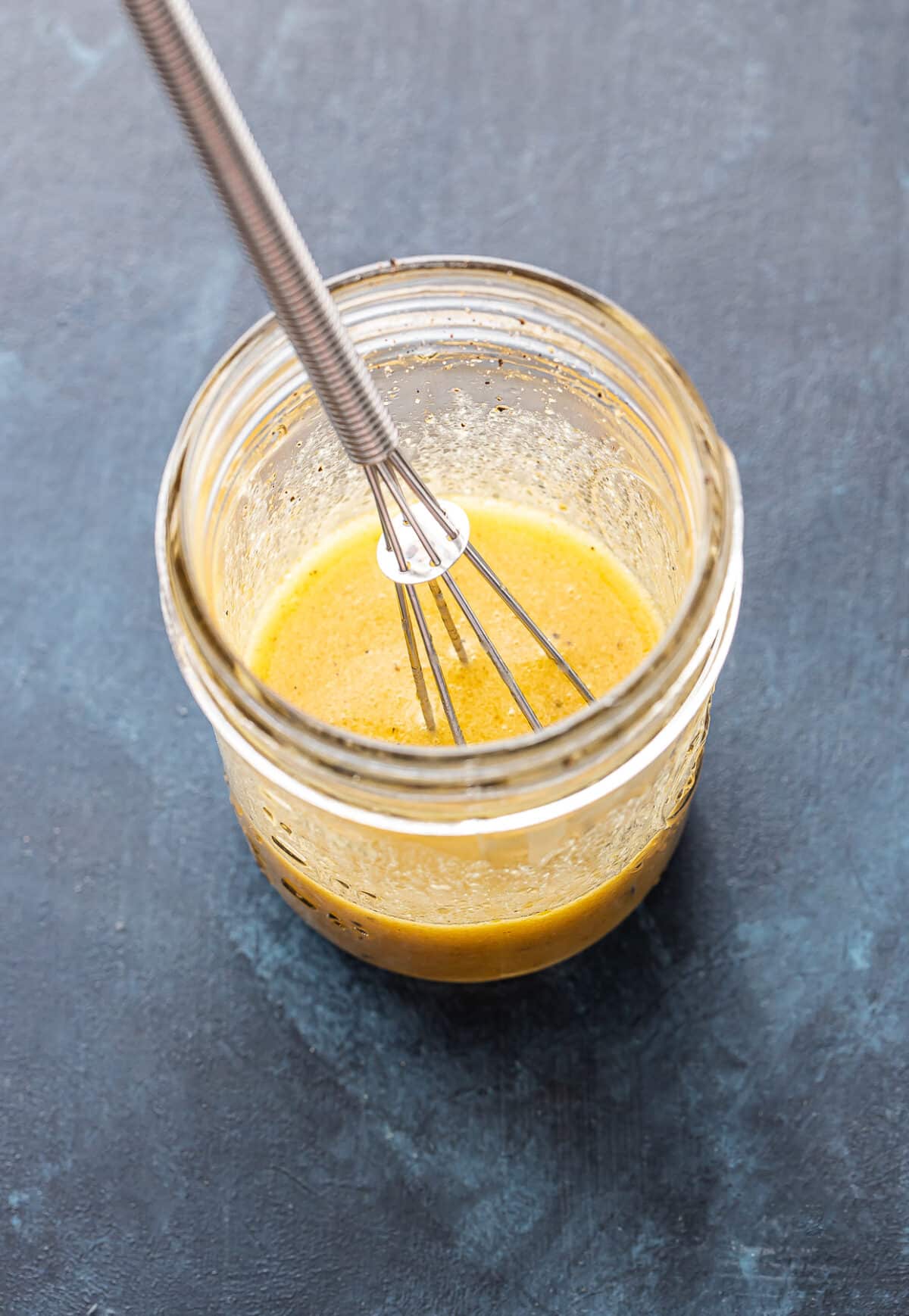 Lemon vinaigrette in a jar with a whisk.