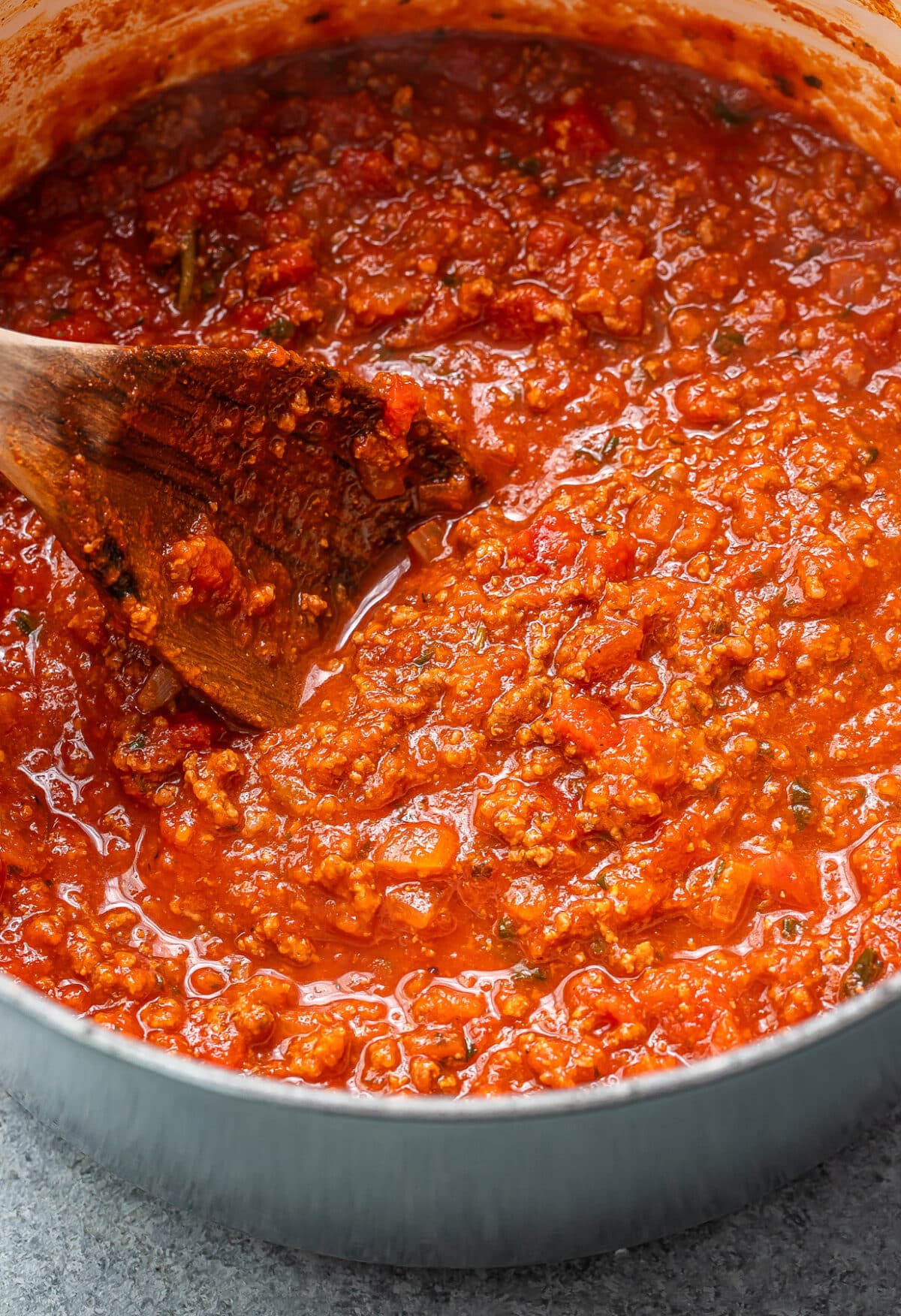 Homemade spaghetti sauce in a pot with a wooden spoon.