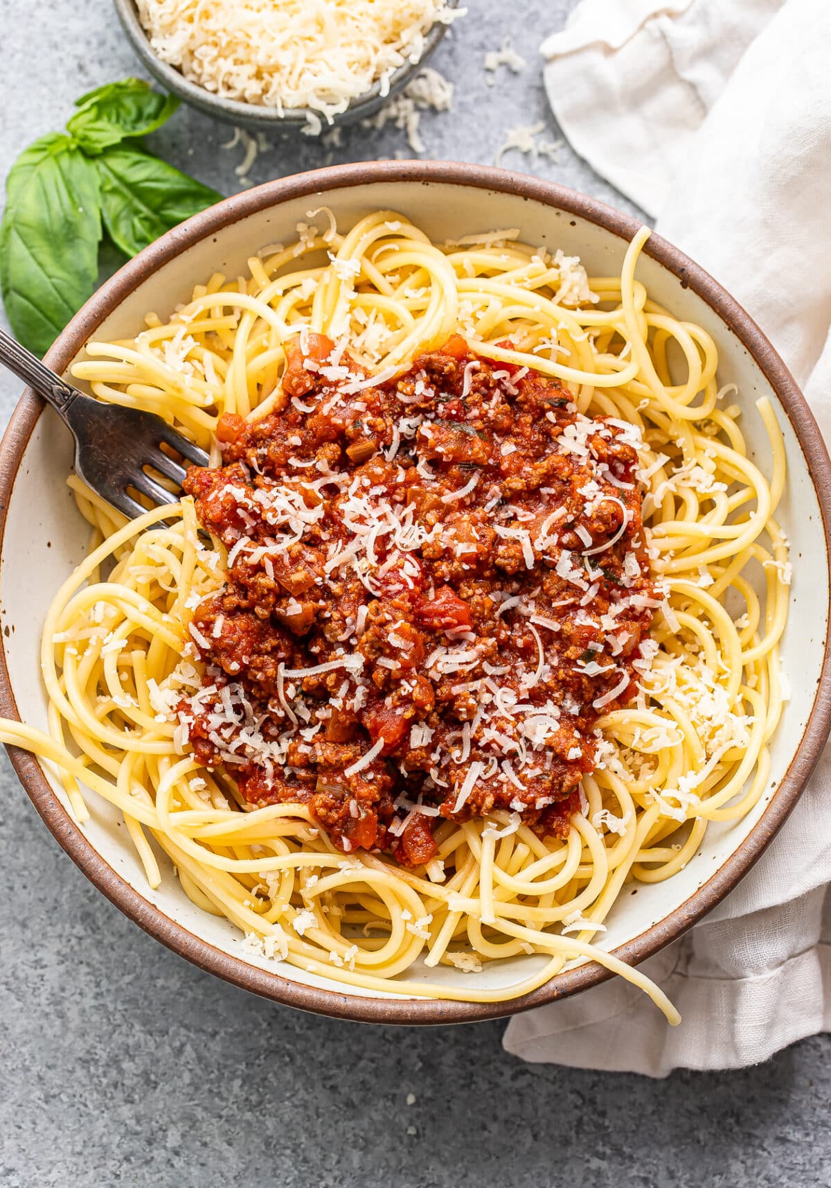 homemade spaghetti sauce on top of spaghetti noodles in a white bowl with a fork. 