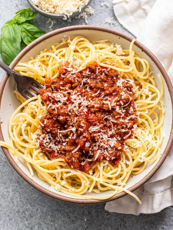 homemade spaghetti sauce on top of spaghetti noodles in a white bowl with a fork.