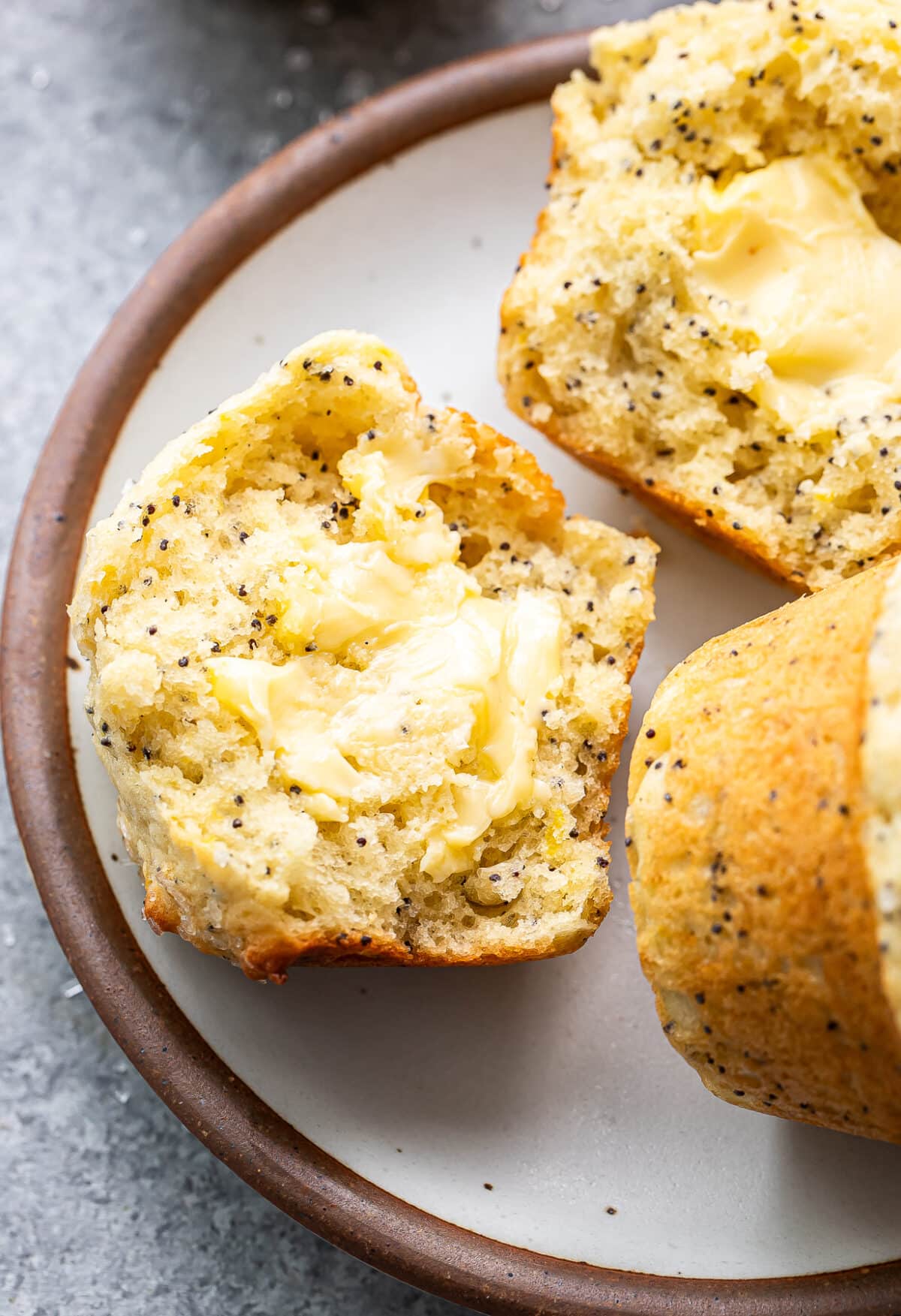 Lemon poppy seed muffin cut in half with butter on it.