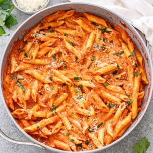 Penne alla vodka in a skillet topped with parmesan cheese and parsley.