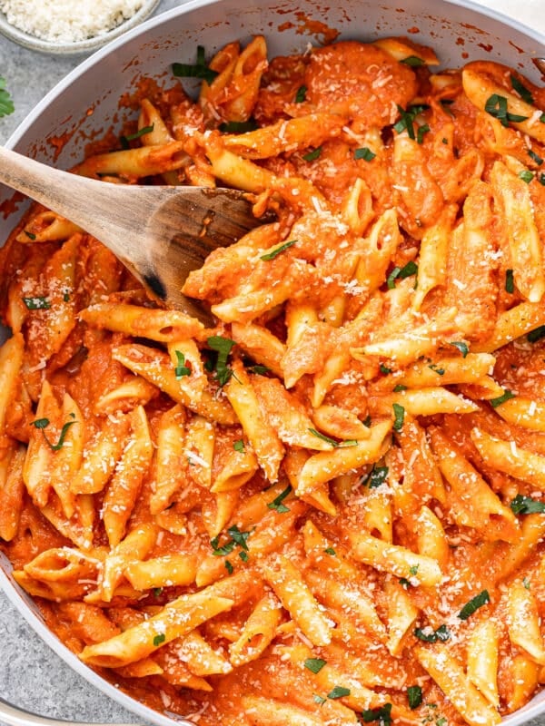 Penne alla vodka in a skillet with a wooden serving spoon.
