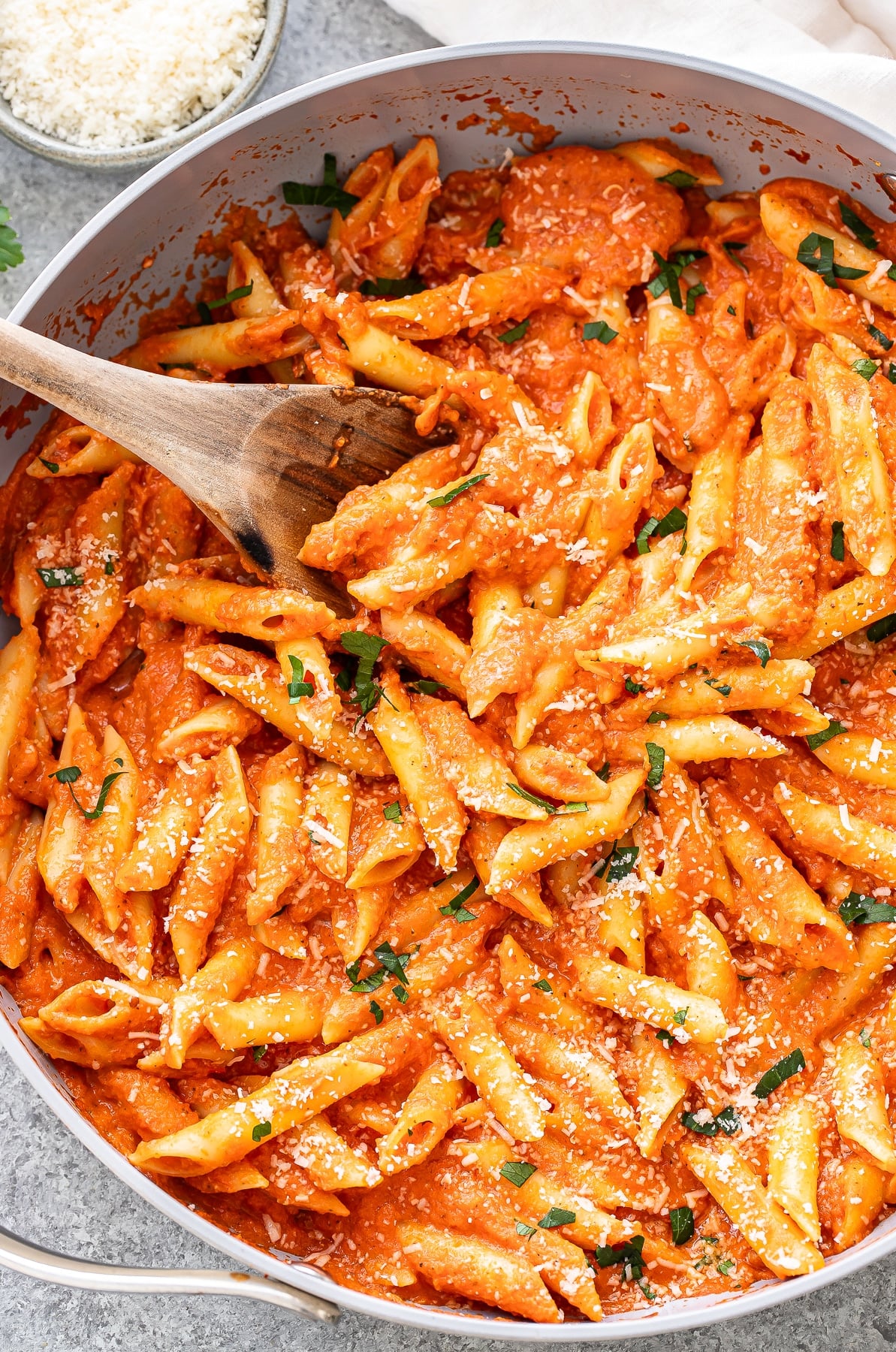 Penne alla vodka in a skillet with a wooden serving spoon.