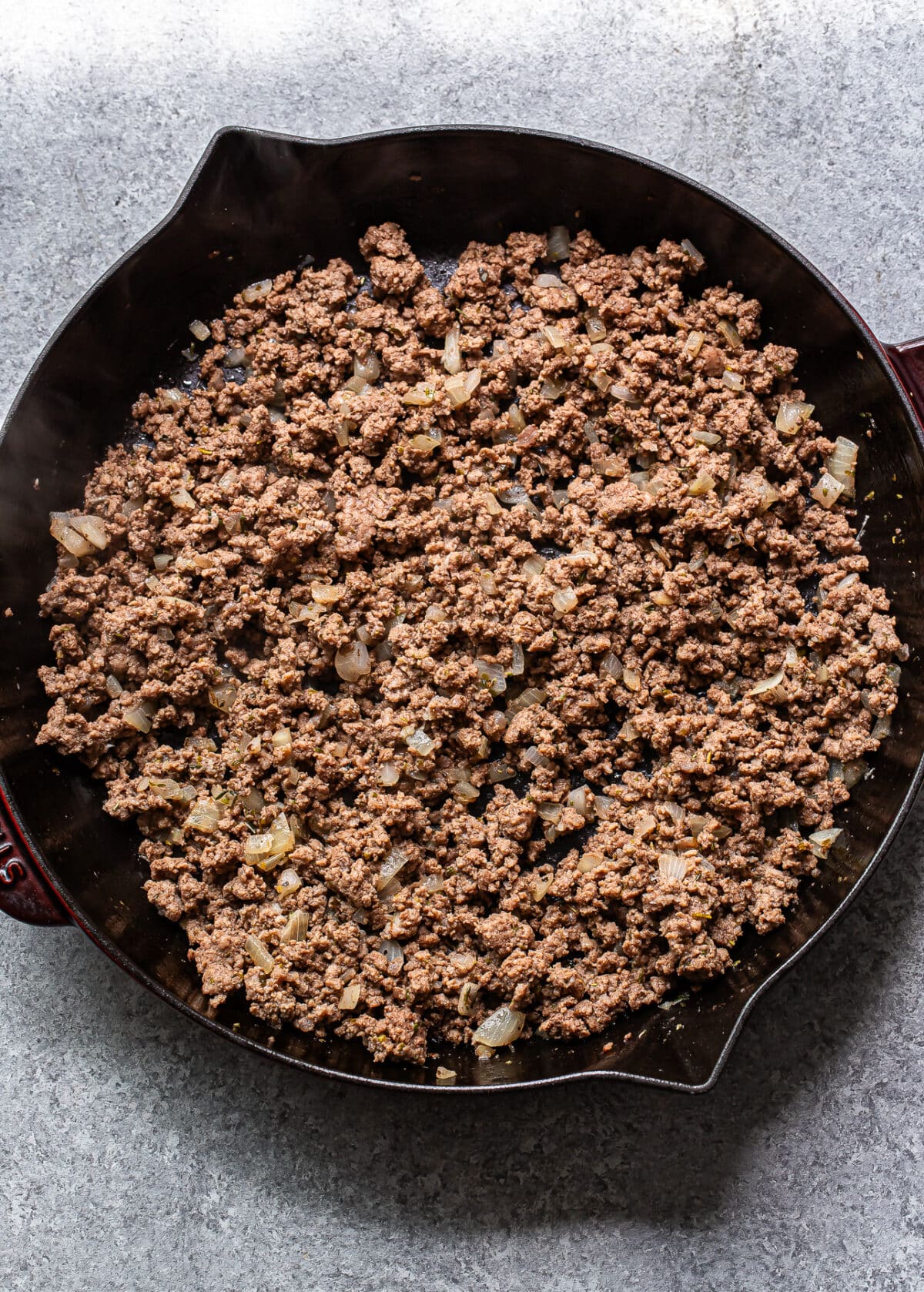 Ground beef and onions in a skillet.